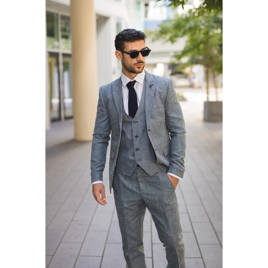 Man wearing a gray suit and sunglasses on a city street.