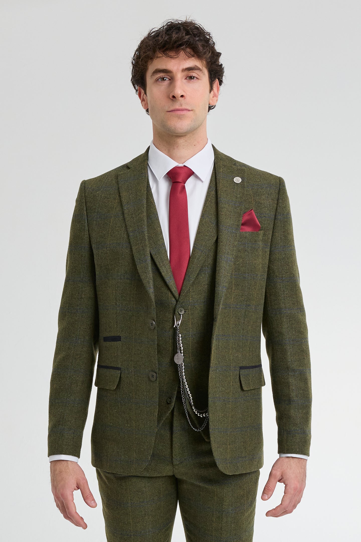 Man wearing a green tweed suit with a red tie and pocket square on a white background