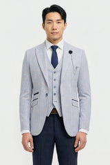 Man wearing a light gray blazer, navy vest, and dark blue tie on a white background