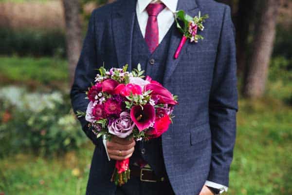 Elegant groom in 3 piece wedding suit and bow-tie with bouquet